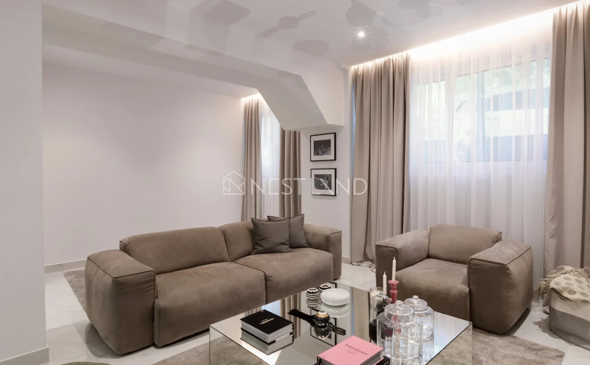 Modern living room with a taupe sofa set, glass coffee table, and sheer curtains.