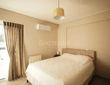 Minimalist bedroom with a beige theme, a large bed, pendant light, and an air conditioner.
