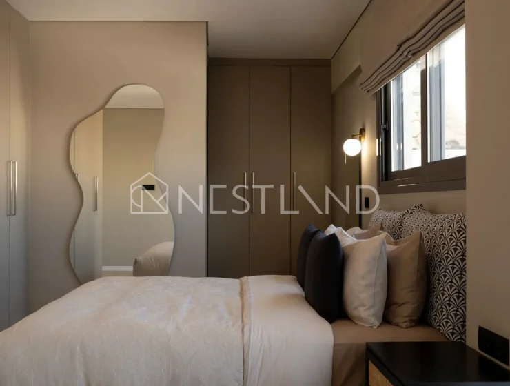 Modern bedroom with a large bed, mirror, and tasteful lighting.