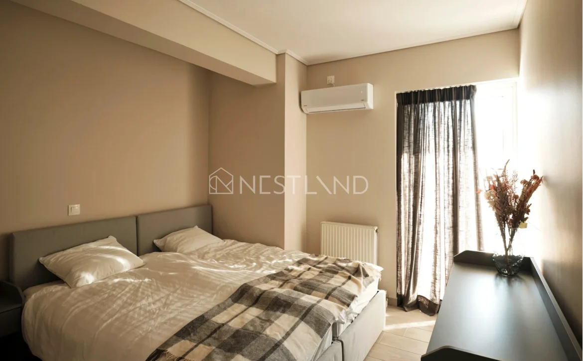 Modern bedroom with a double bed, plaid blanket, air conditioner, and sheer curtains.