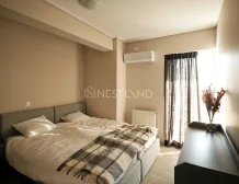 Modern bedroom with a double bed, plaid blanket, air conditioner, and sheer curtains.