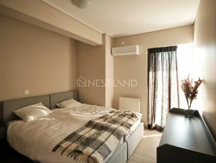 Modern bedroom with a double bed, plaid blanket, air conditioner, and sheer curtains.