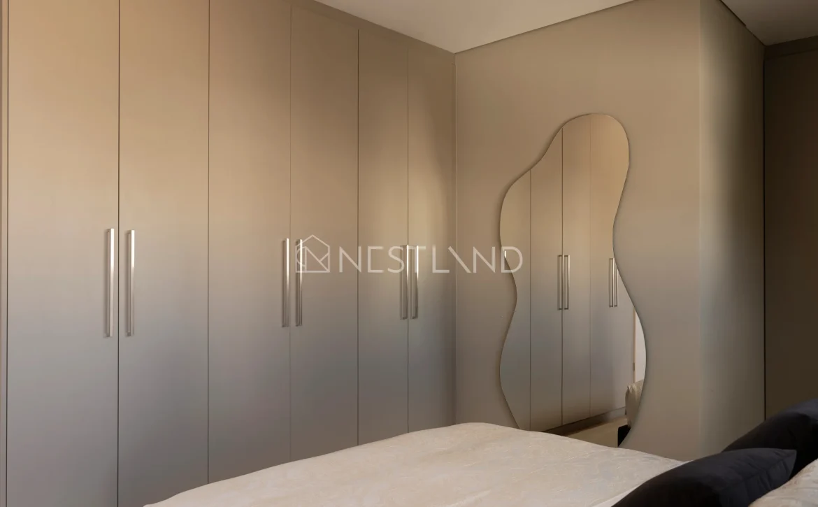 Modern bedroom with a large built-in wardrobe and an elegant mirror.