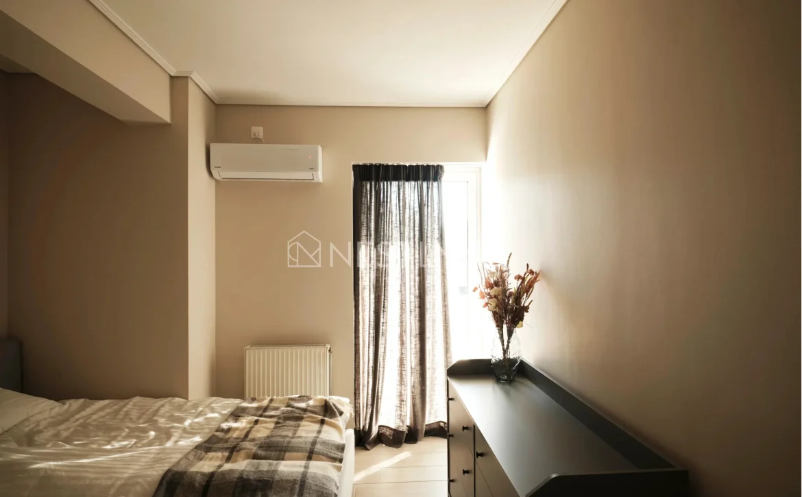 A modern bedroom with a bed, window with curtains, dresser, and an air conditioner.