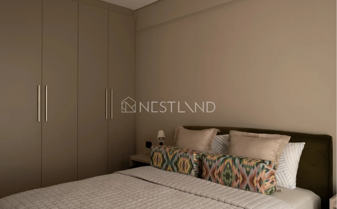 A modern bedroom with a large bed, patterned pillows, and a built-in closet.