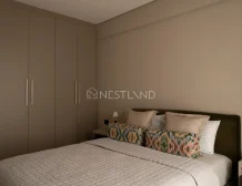 A modern bedroom with a large bed, patterned pillows, and a built-in closet.