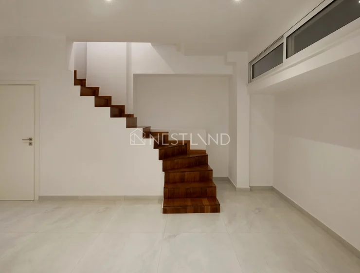 Modern interior with floating wooden staircase, white walls, and marble floor.