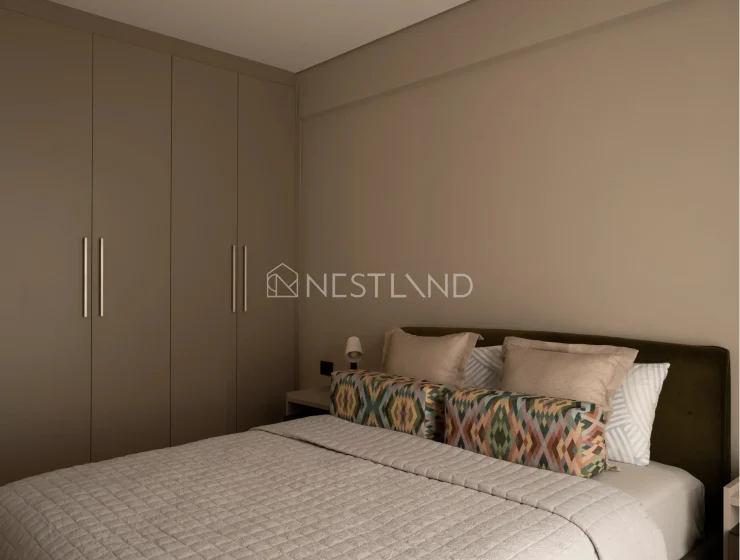 A modern bedroom with a large bed, patterned pillows, and a built-in closet.