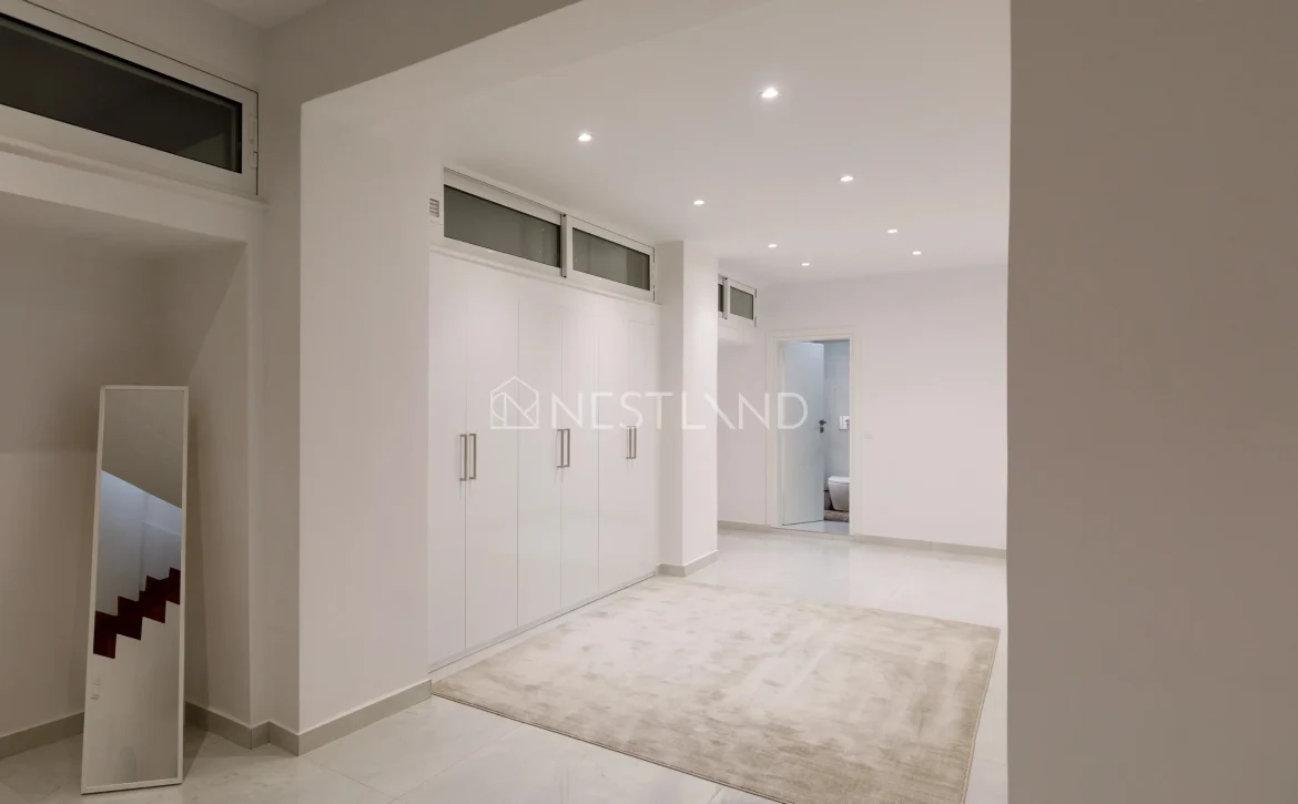 Modern hallway with white cabinetry, a mirror, and a beige rug on a tiled floor.