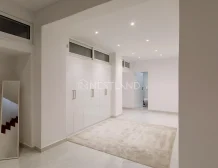 Modern hallway with white cabinetry, a mirror, and a beige rug on a tiled floor.