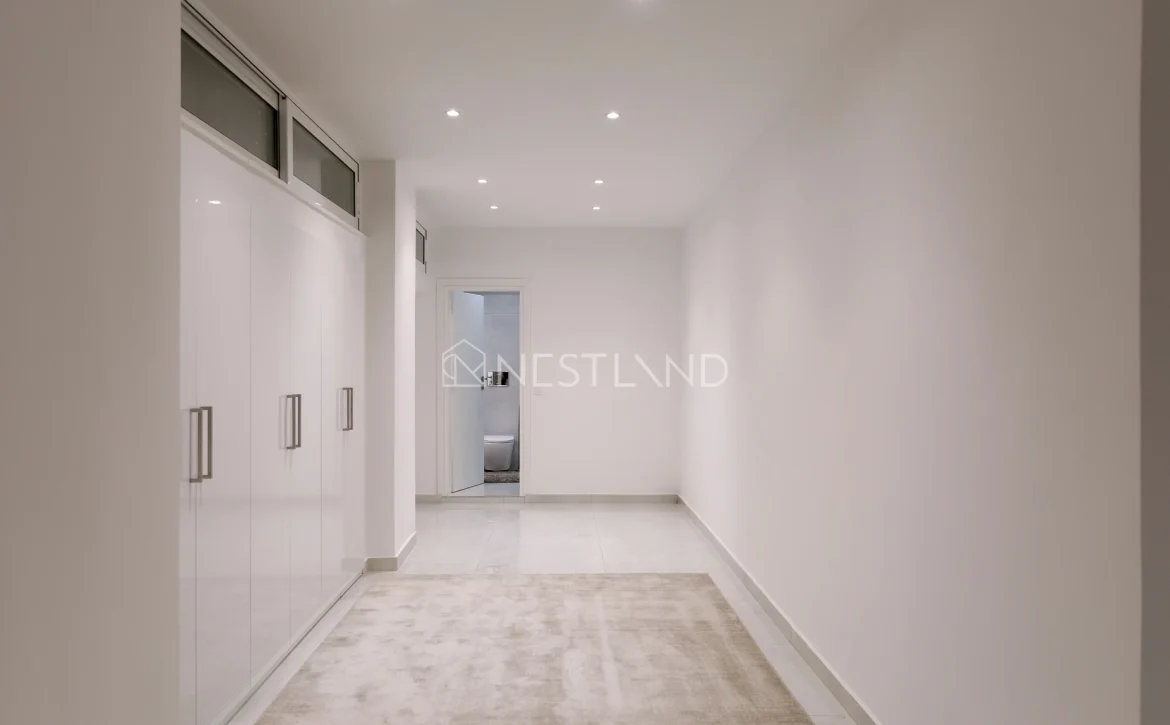Modern hallway with white walls, built-in cabinets, and recessed lighting.