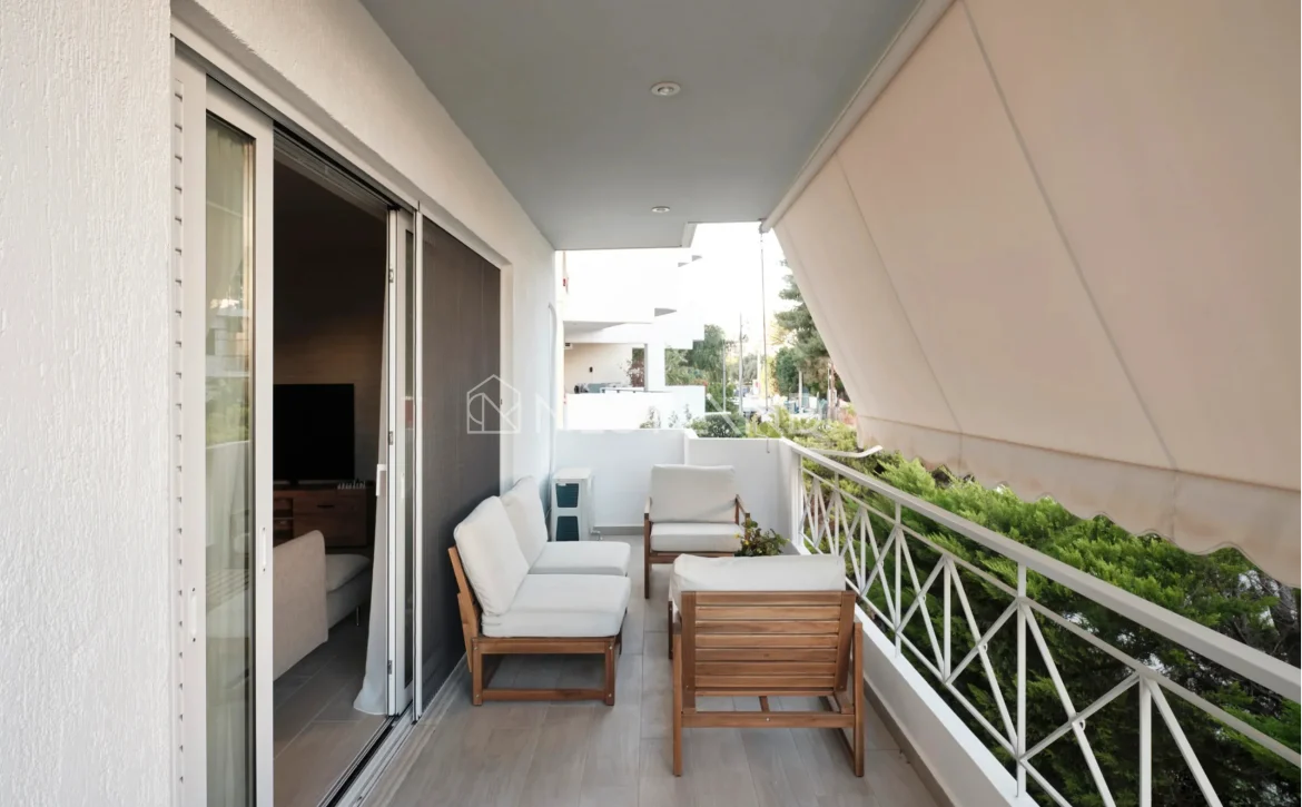 Modern balcony with outdoor furniture, plants, and an awning.