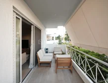 Modern balcony with outdoor furniture, plants, and an awning.