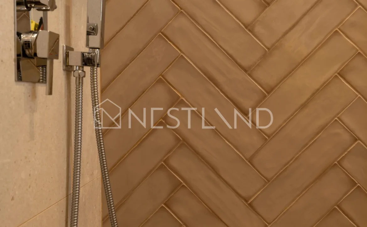 Elegant brown herringbone tile wall with modern shower fixtures on the left side.