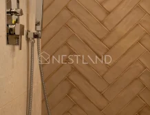 Elegant brown herringbone tile wall with modern shower fixtures on the left side.