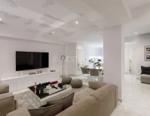 Modern living room with white furniture, marble floor, and dining area in the background.