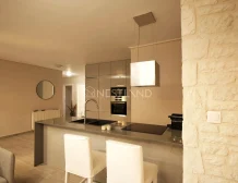Modern kitchen interior with beige cabinets, built-in appliances, and a breakfast bar with stools.
