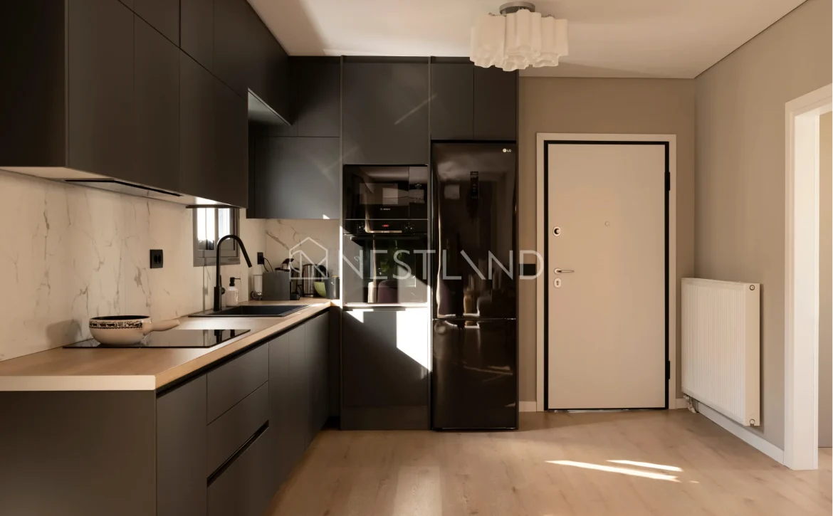 Modern kitchen interior with dark cabinetry, marble backsplash, and stainless steel appliances.