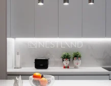 A modern kitchen counter with fruit bowl, plants, and pendant lights.