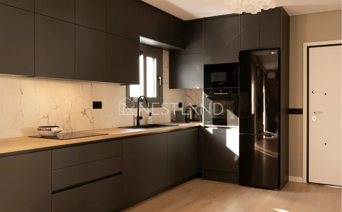 Modern kitchen with dark cabinets, marble backsplash, and sunlight streaming onto a wooden floor.