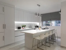 Modern kitchen interior with white cabinets, island, and pendant lights.