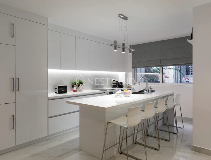 Modern kitchen interior with white cabinets, island, and pendant lights.