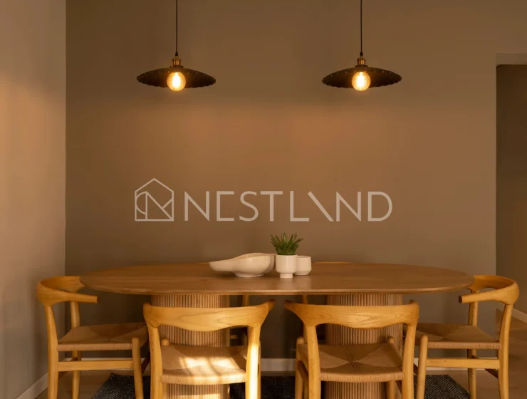 A cozy dining room with a wooden table, chairs, pendant lights, and a herringbone rug.