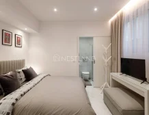 Modern bedroom with a large bed, artwork on the wall, TV, and an en-suite bathroom.