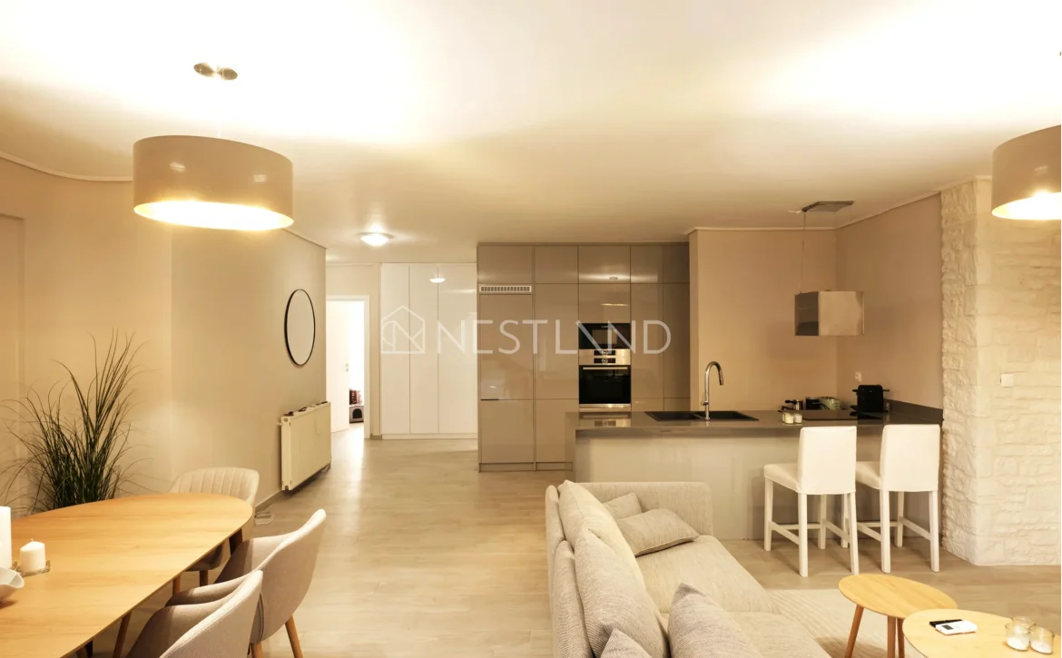 Modern open-plan living room with kitchen, dining area, and beige sofa.