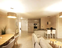 Modern open-plan living room with kitchen, dining area, and beige sofa.