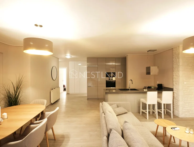Modern open-plan living room with kitchen, dining area, and beige sofa.