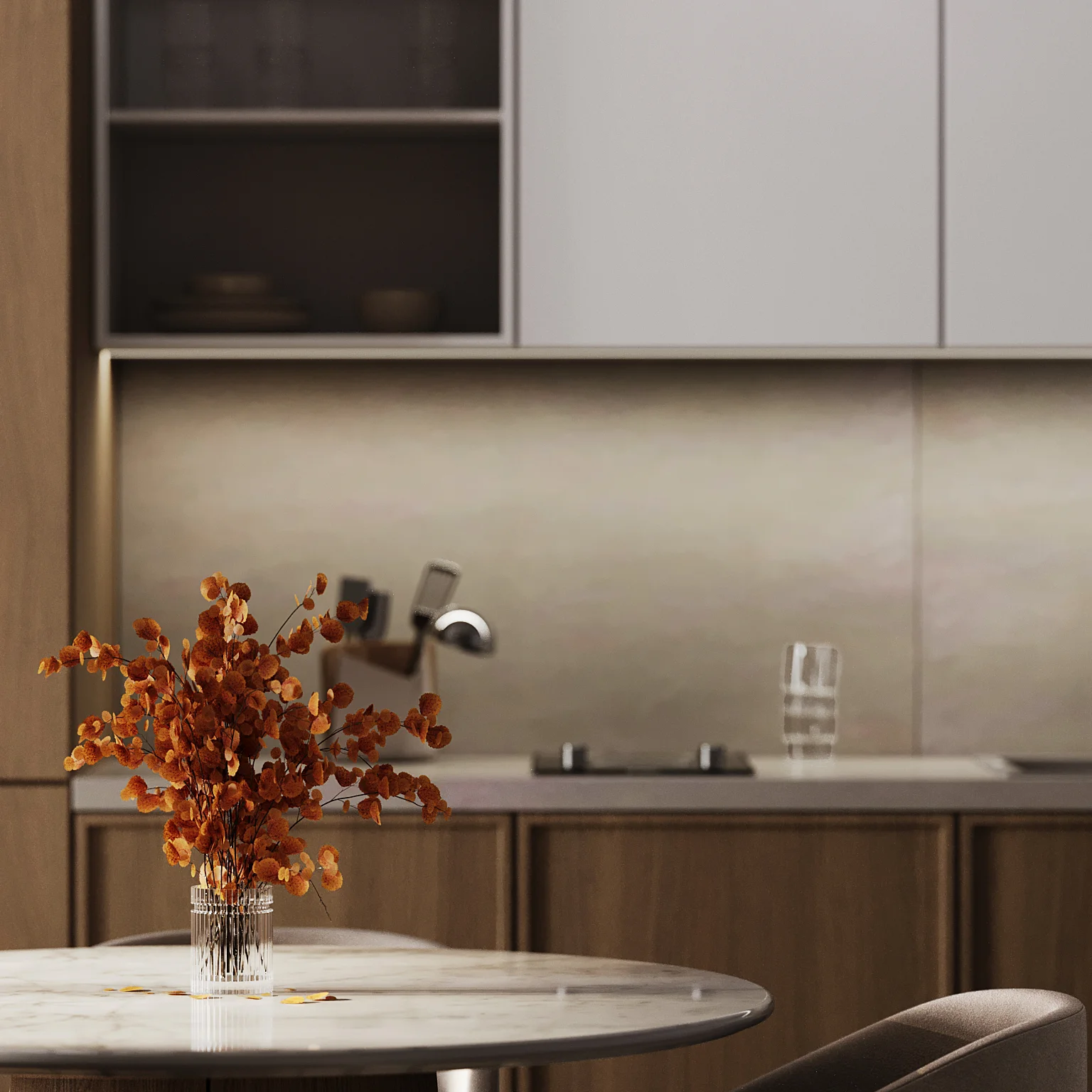 Modern kitchen with a marble-topped table, a vase of orange flowers, wooden cabinetry, and a backsplash. A glass of water and a stovetop are visible in the background.