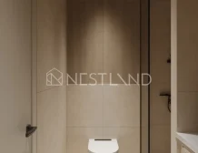 Modern bathroom with a wall-mounted toilet and a washing machine, featuring neutral tones and a glass partition.
