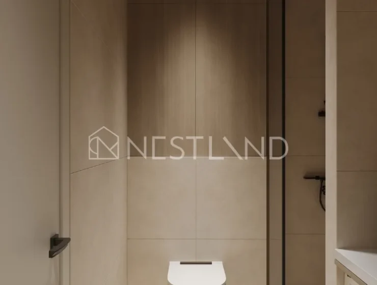Modern bathroom with a wall-mounted toilet and a washing machine, featuring neutral tones and a glass partition.