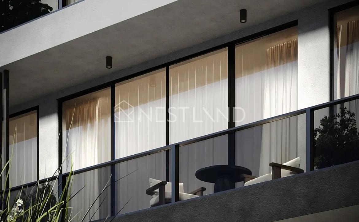 Modern apartment balcony with glass doors, curtains, and outdoor furniture.