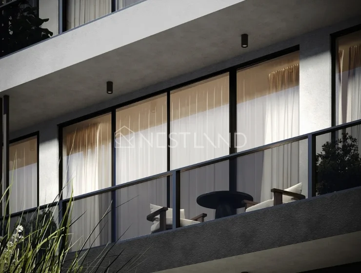 Modern apartment balcony with glass doors, curtains, and outdoor furniture.