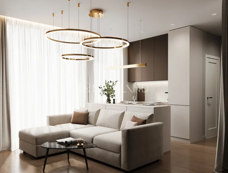 Modern living room with beige sofa, circular hanging lights, and a kitchen in the background.