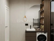 Modern bathroom interior with a pendant light, vanity, towel ladder, and washing machine.